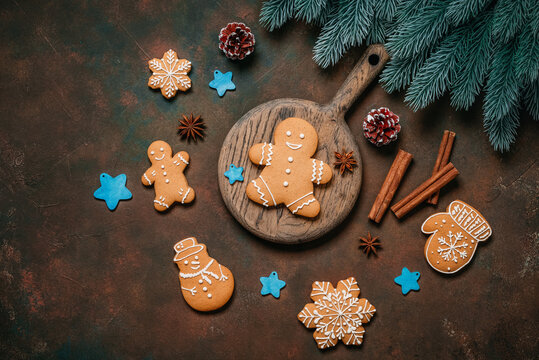 Gingerbread cookies with Christmas decorations on dark brown grunge background, top view, flat lay
