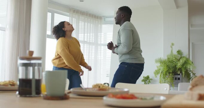 African American couple moving after woman starting rhythmic steps at home table with French press