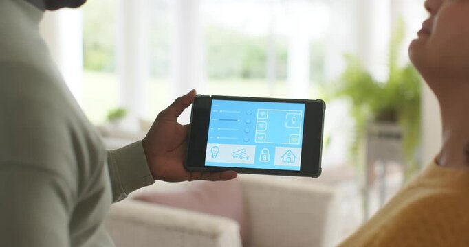 African American couple watching man tapping and sliding tablet controls at home adjusting lights