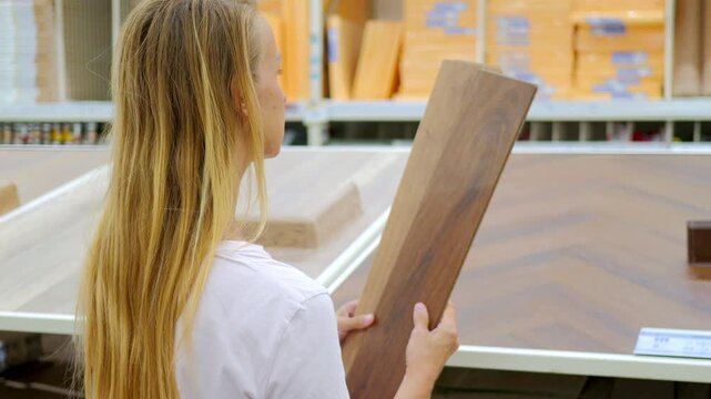 Woman Comparing Laminate Flooring Samples in Home Improvement Store
