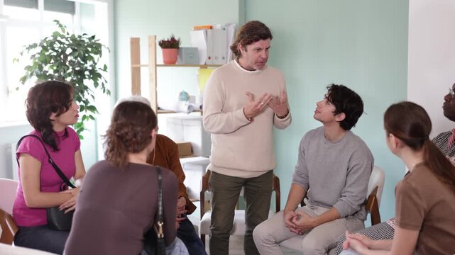 Positive successful man standing communicating with group of adult people at seminar in advanced training. High quality 4k footage