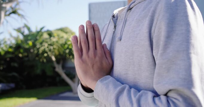 African American man bringing hands together holding palms-pressed at chest in courtyard meditating
