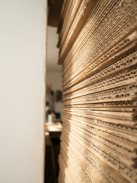 Large stack of corrugated cardboard sheets leaning against a wall in deep shadow