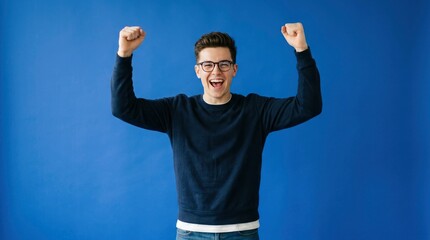 Naklejka premium Excited young man celebrating success with arms raised