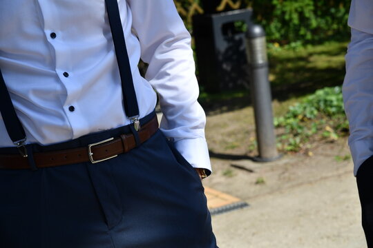 Detailaufnahme eines elegant gekleideten Mannes mit wei&szlig;em Hemd, schwarzer Krawatte und Hosentr&auml;gern im Freien. Hochzeitsgast, Br&auml;utigam, Business-Stil und festliche Herrenmode.