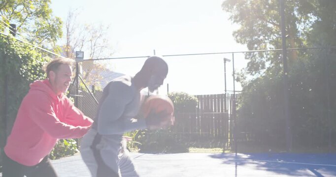 Diverse men playing on blue court guard pressing grey player guarding ball pink player aiming shot