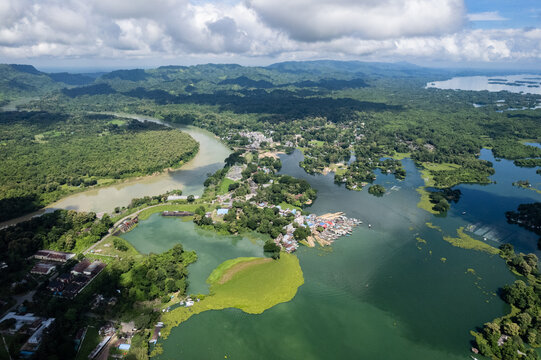 Aerial view of Kaptai Lake surrounded by lush green hills and dense forests with small village settlements along the shoreline in Rangamati Hill District, Chittagong Division, Bangladesh.