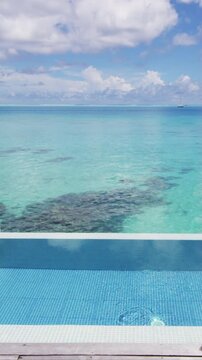Infinity pool over tropical ocean coral lagoon travel vacation background in Slow motion. Raw unedited vertical video of real pool.