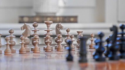 A wooden chess set with intricately carved pieces set up on a polished board inside a classic room © HABI ANGGARA PUTRA