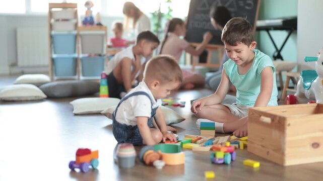 Boys playing together with construction set and toys in front of other children in kindergarten . High quality 4k footage