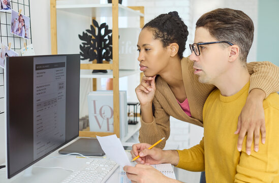 Couple reviewing bill at computer, budgeting payment. They review details, manage utilities and household finances, planning due dates to grow savings. Clear concept of home finance.