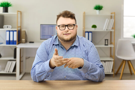 Man businessman office portrait speaking video call. Confident professional gestures in modern office facing camera with smile, ready to help. Theme is remote online meeting and trust.