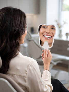 Mulher Sorrindo com Espelho com Formato de Dente em Consult&oacute;rio