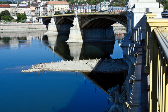 low water level on the Danube river at the Margaret Bridge in Budapest, Hungary. hot temperature, drought. exposed rocky island at the base of the bridge pillar. reflecting water. environment concept