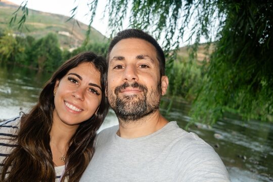 Couple happily taking a selfie outdoors near a riverside in Spain