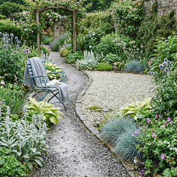 A stone pathway winds through a lush garden filled with various flowers