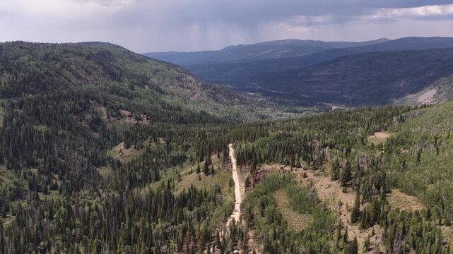 Wide aerial of Soapstone Pass in Wasatch National Forest Utah with dramatic sky with rain shower with dense coniferous forests in summer