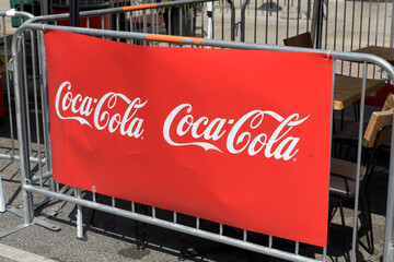 Fototapeta premium Coca-Cola sign pinned to a crowd control barrier fence on the Danforth, Toronto