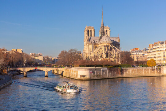 View of Ile de la Cite in Paris, France, with the Seine River, sightseeing boat, historic architecture and waterfront on a clear sunny day.