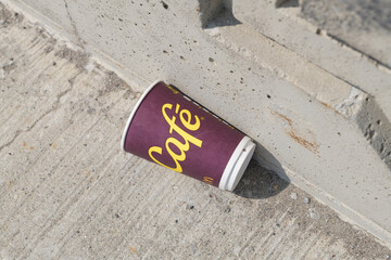 Fototapeta premium discarded McDonald's Canada McCafé beverage cup on a concrete pavement next to a concrete wall in Toronto