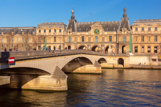 Pont du Carrousel crosses the Seine River in central Paris, France, with historic architecture and pedestrians along the waterfront.