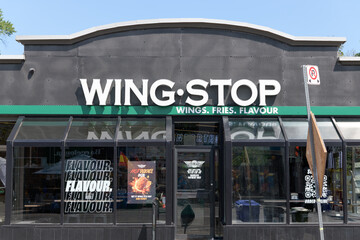 Fototapeta premium exterior building facade and sign of Wingstop, a chicken wings restaurant, located here at 780 Danforth Av, Toronto