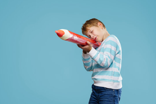 Boy child with XXXL pencils, ready to go back to school. Isolated on free background.