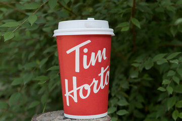 Fototapeta premium close-up of a discarded Tim Hortons beverage cup on a defocused foliage background in Toronto