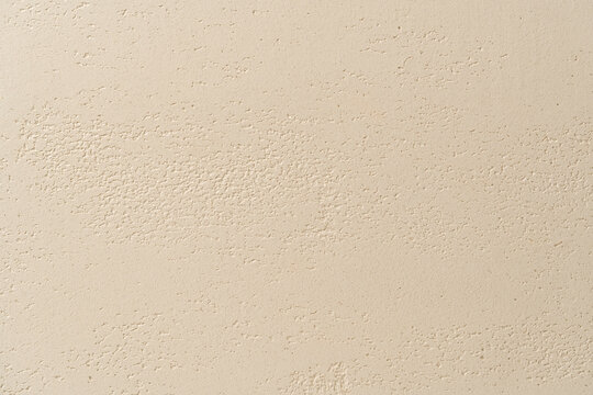 Close-up of a travertine effect decorative plaster wall surface in warm beige and cream tones with porous grain and rough stone-like texture