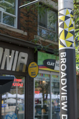 Fototapeta premium Broadview Danforth BIA pole wrap and defocused businesses on Danforth Av near Broadview Av, Toronto