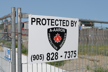 Fototapeta premium metal sign of A-AARON Protection Services fixed to a construction barrier fence, East York, Toronto