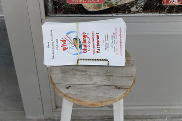 Fototapeta premium old wood stool with a packet of menus outside Pho Challenge, a Vietnamese restaurant, located at 1025 Pape Av (East York), Toronto