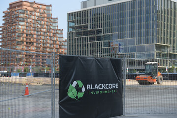 Fototapeta premium Blackcore Environmental banner at a construction site south of Lake Shore Blvd E with defocused view of Aqualuna Condos and T3 Bayside corporate office, Toronto