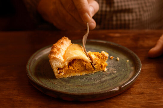 Slice of homemade pie being cut on rustic ceramic plate