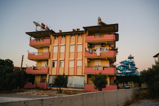 Antalya, Turkey, July 26, 2026: Residential apartment building with rooftop satellite dishes and water park in the background