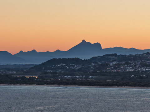 Aerial view of the coastline at Fingal Head with the silhouette of Mount Warning in the background during golden hour, Fingal Head, New South Wales, Australia.