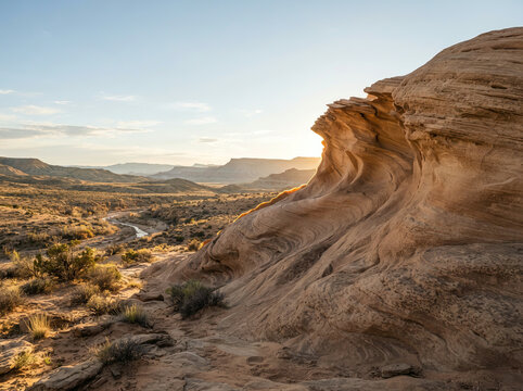 Swirling sandstone formation overlooking a river valley at golden sunset