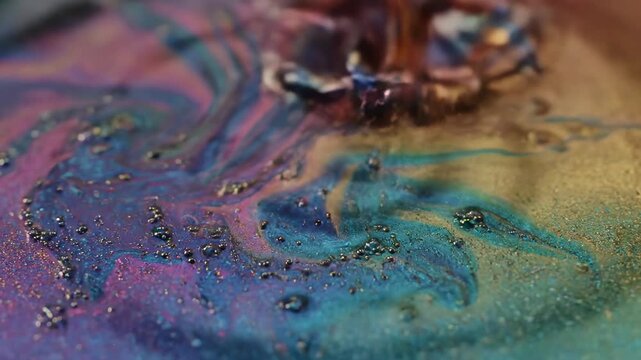 A person sprinkles colored powder on a surface in a craft studio. The powder creates a bright mix of colors and patterns. Different shades blend together as more powder is added