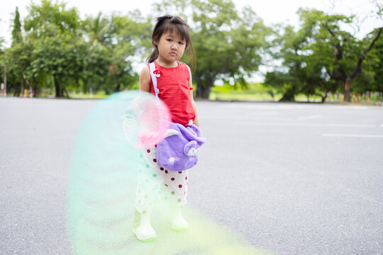Asian little girl playing with colorful spring toy outdoors in the park,Adorable Asian little girl wearing a red shirt and white polka dot pants holding and playing with a vibrant colorful plastic.