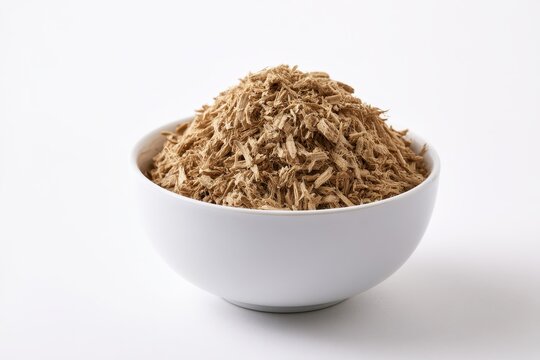 Shredded slippery elm bark in a small ceramic bowl on a white studio backdrop, side view