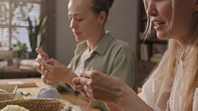Caucasian women crocheting with purple yarn and needles during creative workshop. Video is ideal for promoting hobby classes or handmade craft businesses
