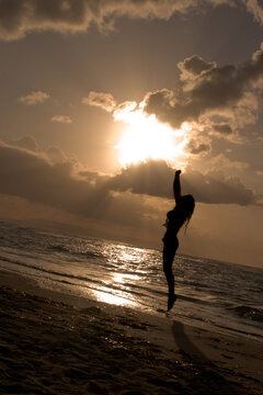 Girl jumping at sunrise at the beach