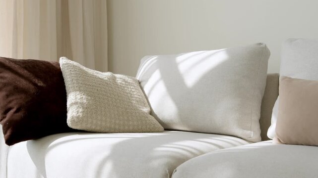 Cozy white sofa with decorative pillows in bright living room interior