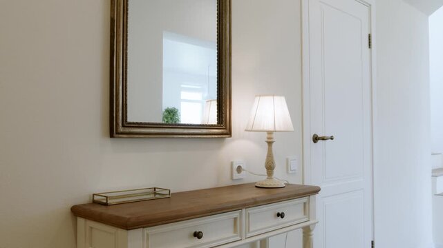 Elegant hallway with console table, mirror and table lamp in country house