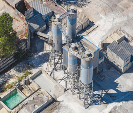 Aerial view of industrial storage silos, processing equipment and infrastructure at an aggregate production facility in Valence, Auvergne-Rhone-Alpes, France.