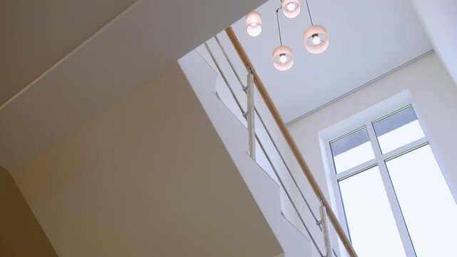 Modern ceiling light fixture in a bright residential interior. Minimalist chandelier with three glass lamps on a white ceiling, viewed from below.