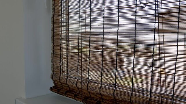 Window with woven bamboo blind and natural daylight in country house interior