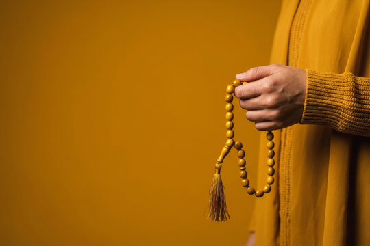 Person holding yellow prayer beads