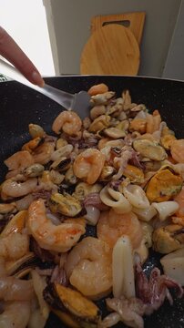 Mixed Seafood Is Stir Fried in a Speckled Pan, Showing Shrimp Squid and Mussels During Home Food Preparation Slow motion Vertical video.