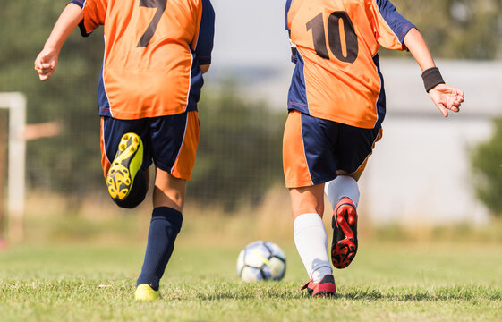Young Soccer Players Chasing the Ball During Outdoor Football Match